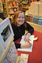 Load image into Gallery viewer, Woman signing a book at a table with books and a computer in the background